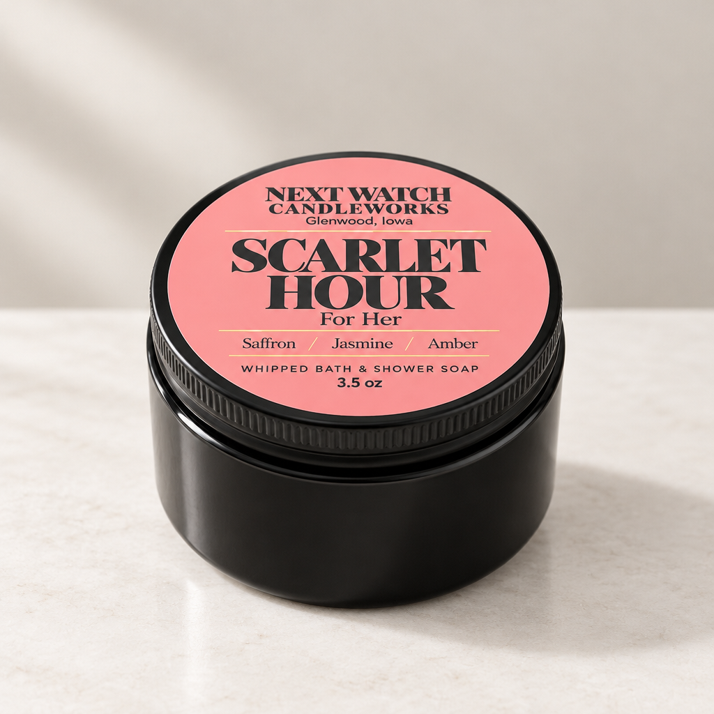 A black metal jar of Next Watch Candleworks 'Scarlet Hour' whipped bath and shower soap, featuring a pink label with black text, set on a light marble surface with a neutral background.