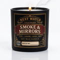A white soy wax candle in a clear glass jar with a decorative black, red, and gold label reading 'NEXT WATCH CANDLEWORKS' and 'SMOKE & MIRRORS'. The candle is photographed on a black reflective surface against a black background.