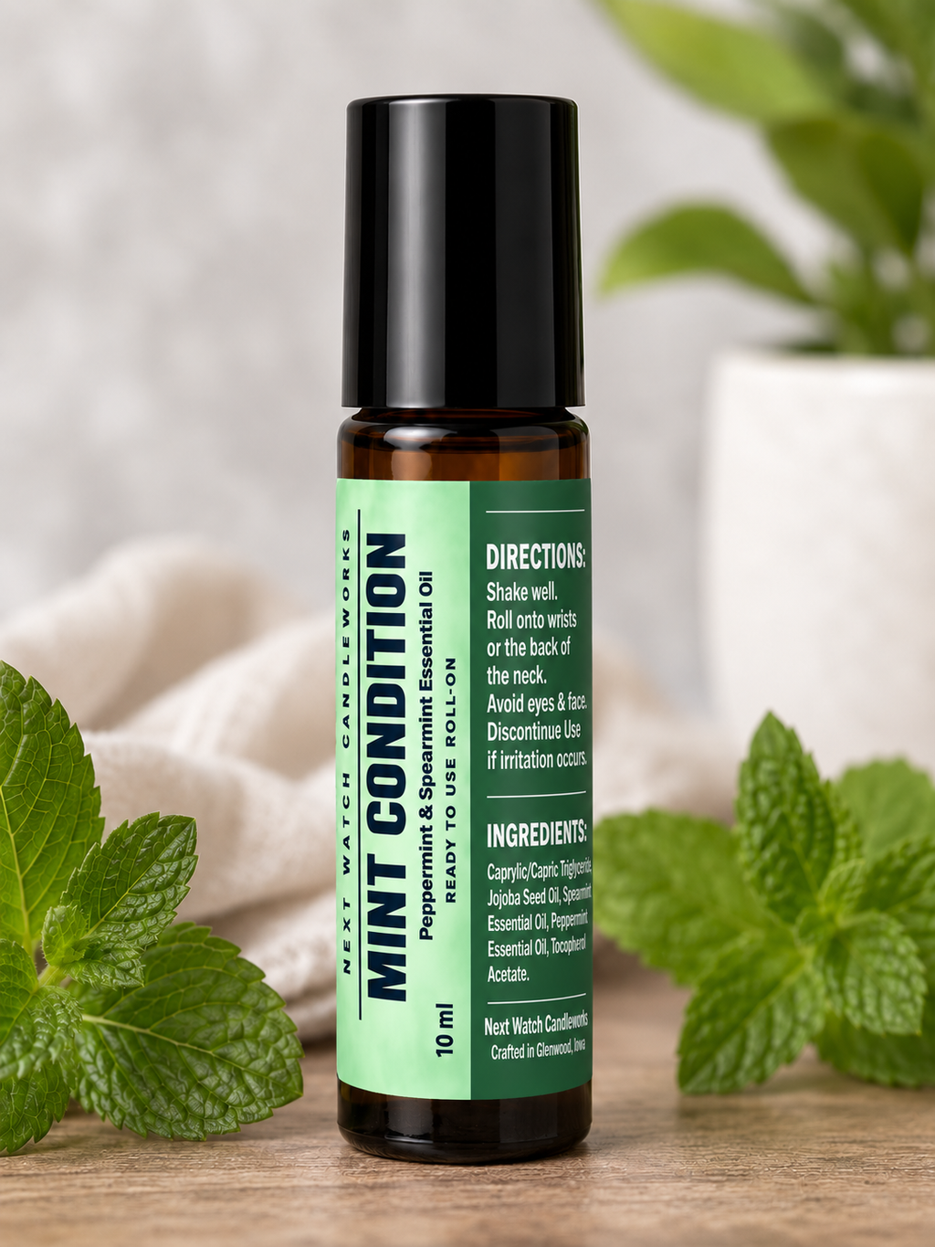 A 10 ml roll-on bottle of Mint Condition Peppermint Essential Oil by Next Wave Cosmetics, styled on a wooden surface with fresh mint leaves and a soft neutral background.