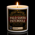 A white ceramic candle jar with a decorative black, red, and gold label reading 'NEXT WATCH CANDLEWORKS' and 'PALO SANTO PATCHOULI'. The candle is photographed on a black background with warm light glowing around the jar edges and a reflection below.